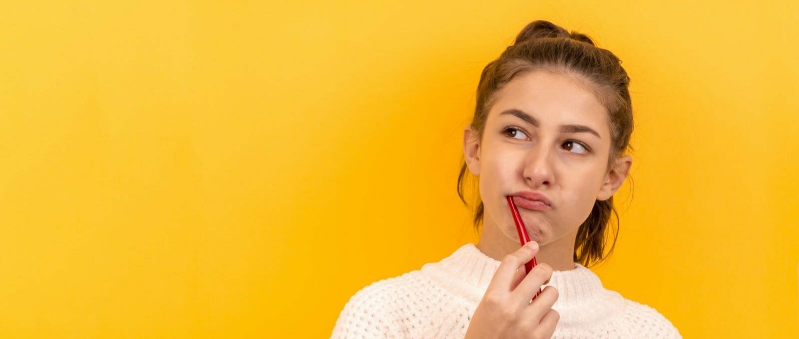Mulher escovando os dentes com cara de desconfiança e medo de dentista