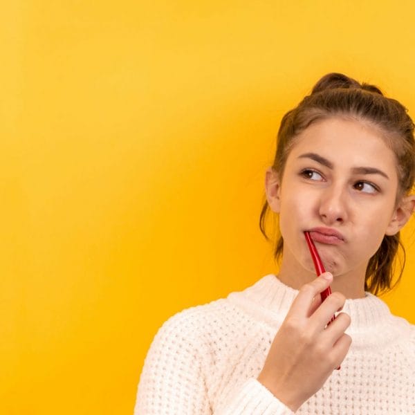Mulher escovando os dentes com cara de desconfiança e medo de dentista
