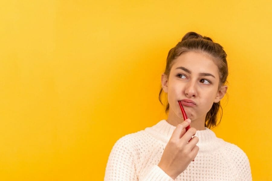 Mulher escovando os dentes com cara de desconfiança e medo de dentista