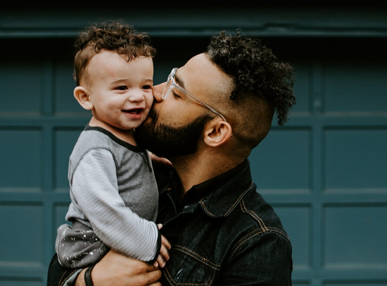 pai segura um bebê no colo e dá beijo na bochecha