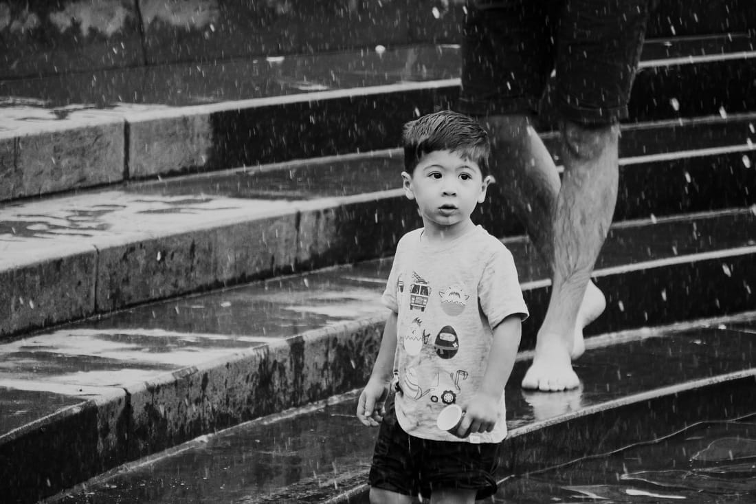 Pai e filho andando na chuva em uma escadaria