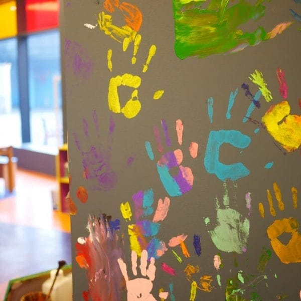 Parede com várias marcas de mãos feitas com tinta, representando o conceito de deixar o filho desenhar nas paredes