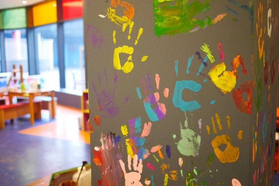 Parede com várias marcas de mãos feitas com tinta, representando o conceito de deixar o filho desenhar nas paredes