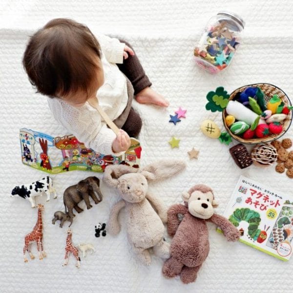 Bebê sentado no chão com diversos brinquedos espalhados ao redor